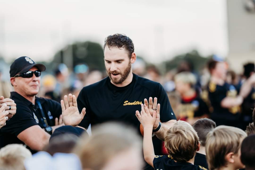 Coach Hopper high-fiving young athletes on the sideline